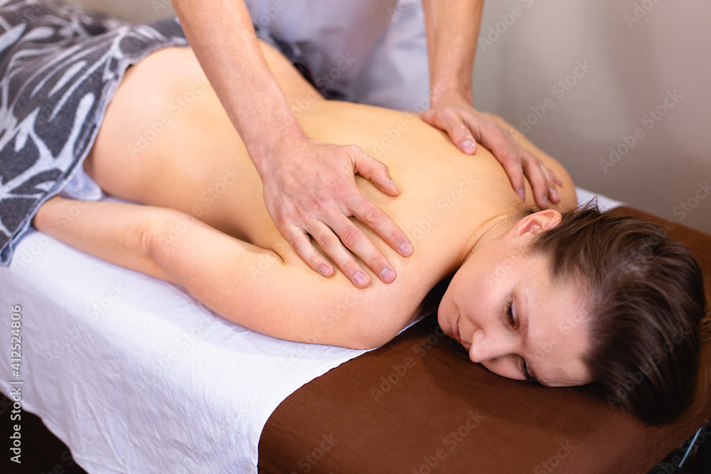 Male massage therapist does back massage to young woman in spa room Male massage therapist does back massage to young woman in spa room