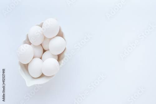 White eggs in a white dish on a light background. Copy space for text. Top view