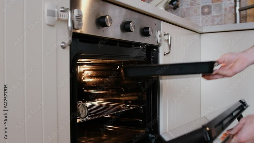 A handsome pastry chef puts muffin dough in the oven. Cooking at home step by step. A handsome pastry chef puts muffin dough in the oven. Cooking at home step by step.