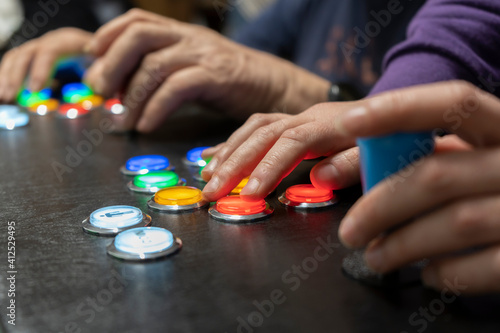 Closeup view of two people hands playing arcade vintage video games.Gamepad with joystick and many colorful buttons .Playful friends, fun and hobbies lifestyle, gaming concept.