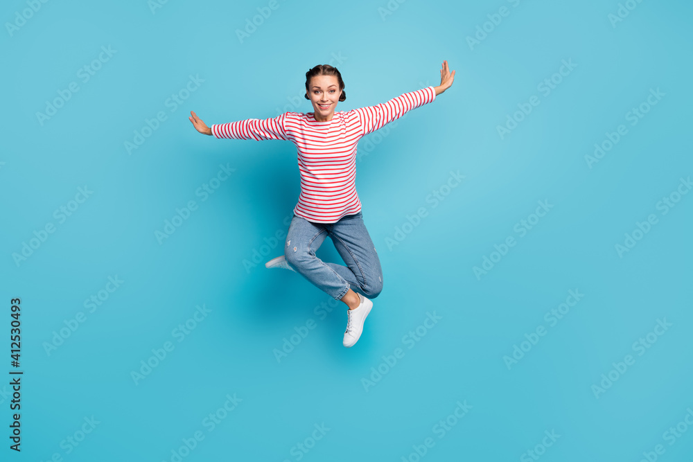 Full size photo of young attractive girl happy smile jump up hands wings fly isolated over blue color background