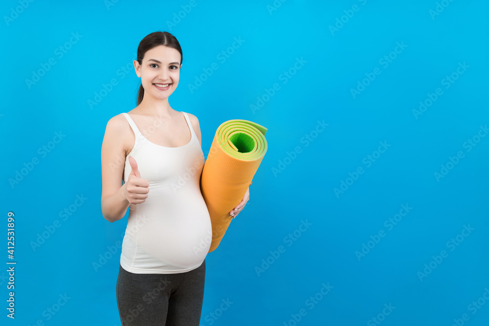 Pregnant Girl Holding Yoga Mat Standing Over Colored Background. Studio Shot, Free Space For Design Pregnant Girl Holding Yoga Mat Standing Over Colored Background. Studio Shot, Free Space For Design