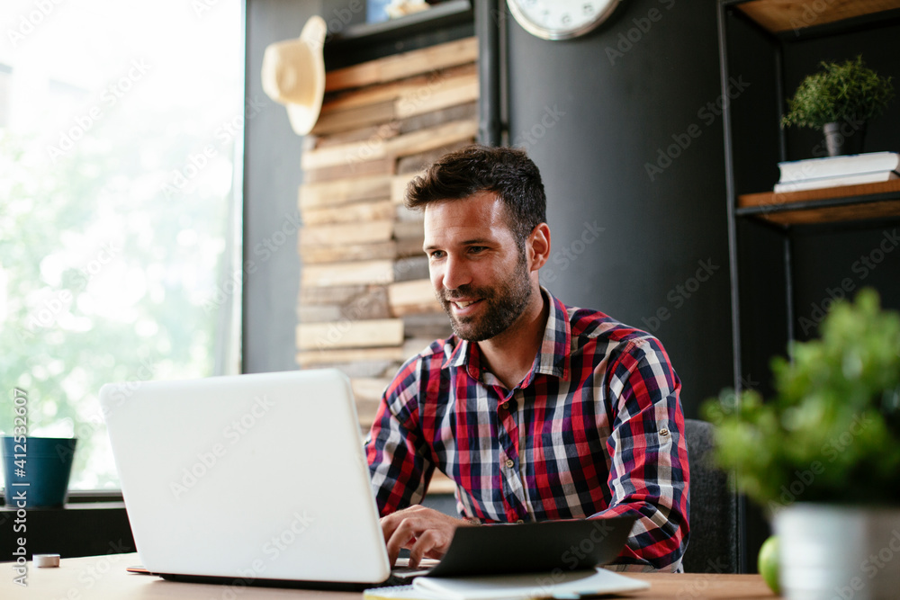 Young businessman working on laptop at office. Businessman sitting at office desk working on new project Young businessman working on laptop at office. Businessman sitting at office desk working on new project
