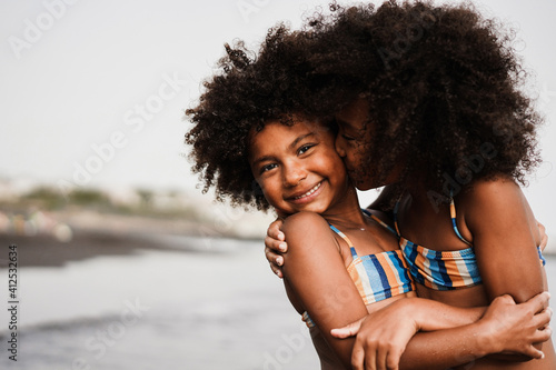 Black sister twins having fun on the beach during summer time - Love and family union concept - Main focus on left child face