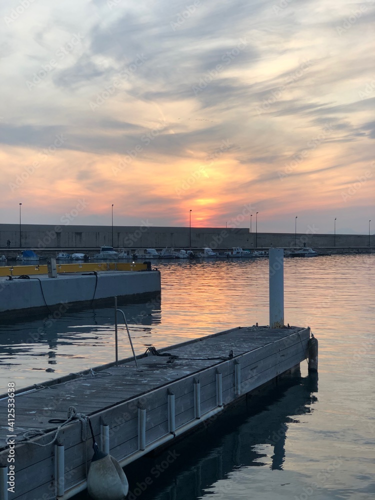 Atardecer con el cielo anaranjado y rosado en la playa cerca del mar en el puerto nautico