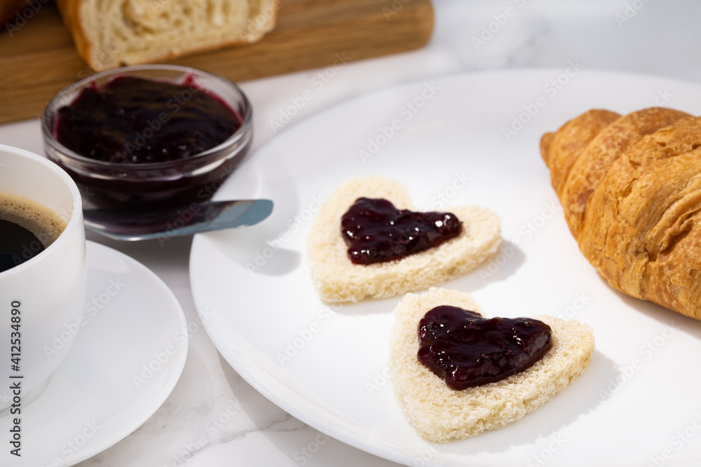 fresh croissants with jam and coffee on light background. Heart shaped toast breakfast for Valentine's Day fresh croissants with jam and coffee on light background. Heart shaped toast breakfast for Valentine's Day