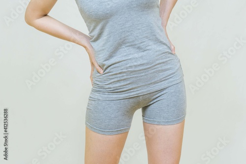 Selective focus of a woman standing over gray background with her hands on her hips and waist,Backache, female suffering from back pain.