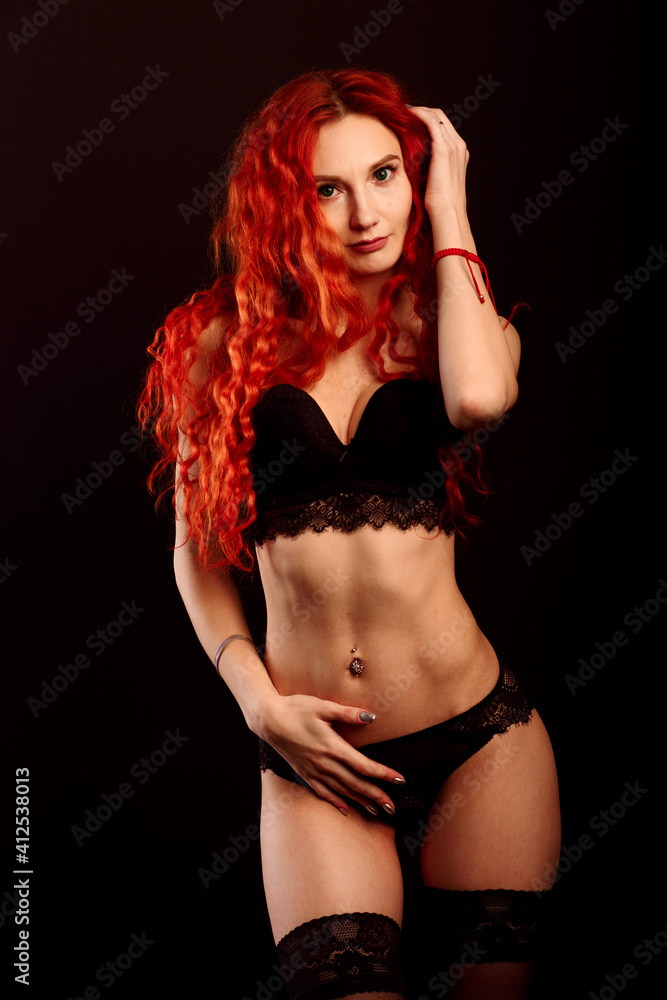 Fototapeta premium Studio portrait of young attractive woman model with redhead long curly hair, in underwear.