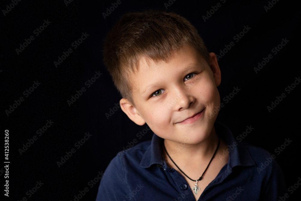 Selective focus, Cheerful calm boy 8-10 years old in a dark polo shirt on a dark background Selective focus, Cheerful calm boy 8-10 years old in a dark polo shirt on a dark background