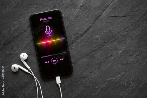 Earphones and mobile phone with podcast app on screen photo