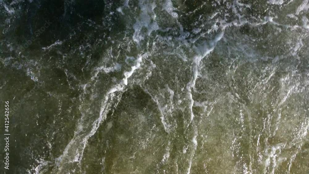 Top view of the turbulent surface of the water. The waves are churning, the river rushing, the place next to the waterfall. Top view of the turbulent surface of the water. The waves are churning, the river rushing, the place next to the waterfall.