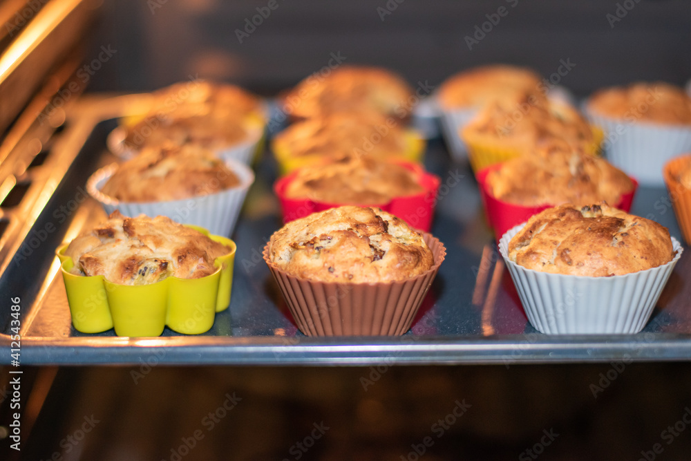 Muffins with dried fruits are baked in the oven in multi-colored silicone molds. Close-up of baked goods in the oven. Place for an inscription. Muffins with dried fruits are baked in the oven in multi-colored silicone molds. Close-up of baked goods in the oven. Place for an inscription.