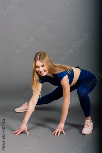 Studio photo of young caucasian female athlete. Slim blonde woman wearing sportwear