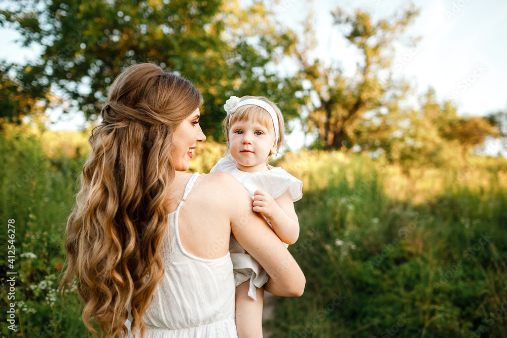 Portrait of a daughter toddler hugging mother on nature on summer day vacation. Mom and girl playing in the park at the sunset time. Concept of friendly family. mother's day Portrait of a daughter toddler hugging mother on nature on summer day vacation. Mom and girl playing in the park at the sunset time. Concept of friendly family. mother's day