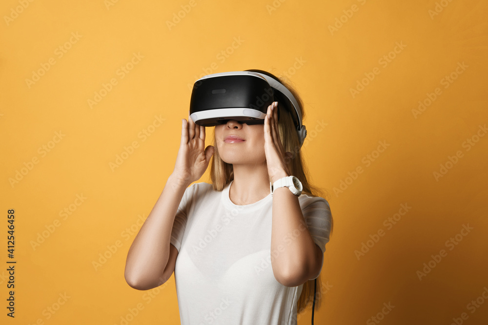Portrait of young blonde woman in white t-shirt VR glasses technology advanced user operating in augmented reality over background with free copy space. Modern cyber technologies concept Portrait of young blonde woman in white t-shirt VR glasses technology advanced user operating in augmented reality over background with free copy space. Modern cyber technologies concept