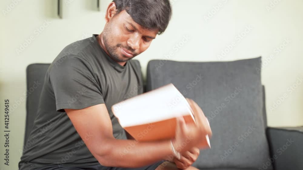 Selective rack focus from Hands to Face, Young man doing exercise using book due coronavirus covid-19 pandemic lock down - concept of new normal, home gym, health care and lifestyle. Selective rack focus from Hands to Face, Young man doing exercise using book due coronavirus covid-19 pandemic lock down - concept of new normal, home gym, health care and lifestyle.