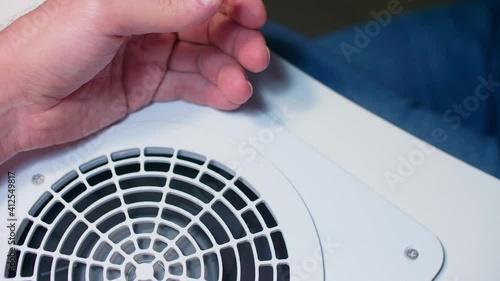 Focused view of fan. Defocused view of client and manicurist hand. Manicurist removes dry skin around nail. Process of manicure. photo