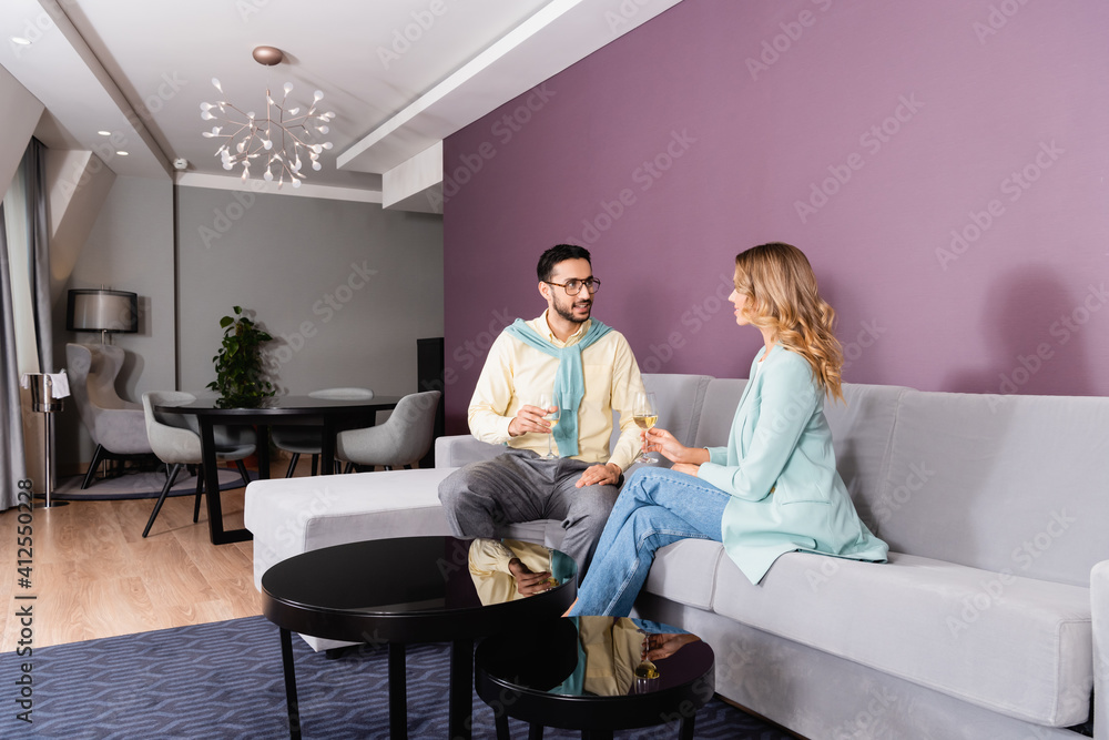 Smiling muslim man looking at girlfriend with glass of wine in hotel Smiling muslim man looking at girlfriend with glass of wine in hotel