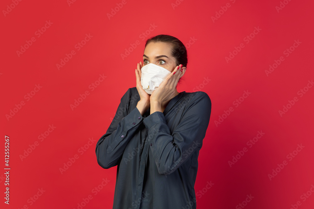 Shocked, scared. Woman in protective face mask isolated on red studio background. New rules of COVID spreading prevention. Copyspace for ad. Pandemic, healthcare and medicine, coronavirus concept. Shocked, scared. Woman in protective face mask isolated on red studio background. New rules of COVID spreading prevention. Copyspace for ad. Pandemic, healthcare and medicine, coronavirus concept.