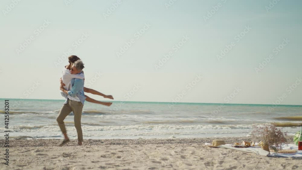 beautiful luaghing joyful man and woman ambracing on beach at seaside and man puts his girlfriend on hands and back like piggyback. lovely couple having fun together at sunny day on sea vacation beautiful luaghing joyful man and woman ambracing on beach at seaside and man puts his girlfriend on hands and back like piggyback. lovely couple having fun together at sunny day on sea vacation