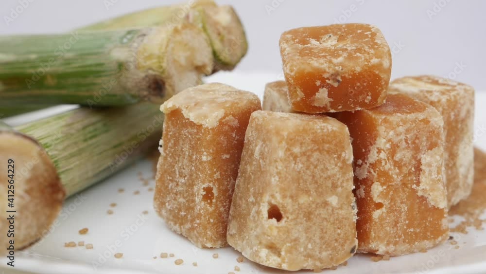 Sugarcane Jaggery view with small raw sugarcane sticks around Sugarcane Jaggery view with small raw sugarcane sticks around