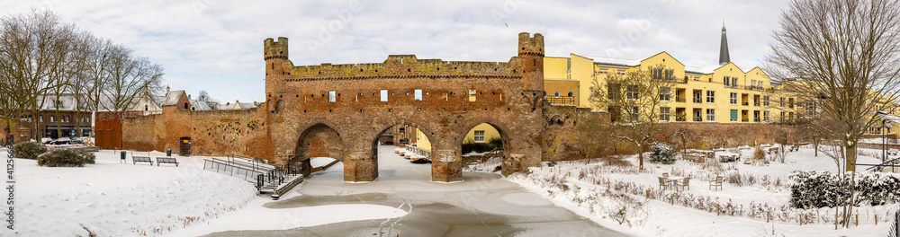 Panoramic wide picturesque view of Berkelpoort entrance portal to historic city centre of Hanseatic Zutphen in The Netherlands in winter after a snow storm