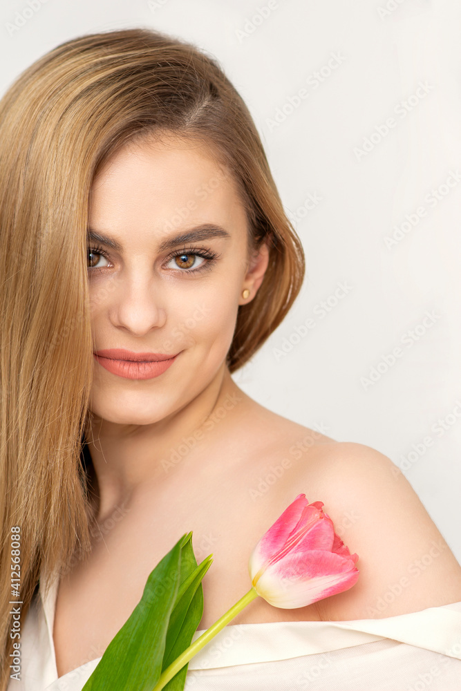 Beautiful caucasian young woman with one tulip against a white background Beautiful caucasian young woman with one tulip against a white background