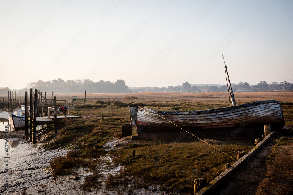 Old boat at Thornham old harbour, Norfolk, England in early morning light, backlit