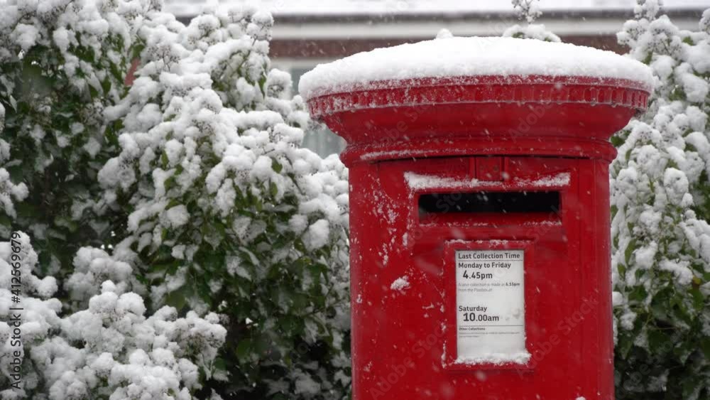 A Red post box in the falling snow at Christmas A Red post box in the falling snow at Christmas