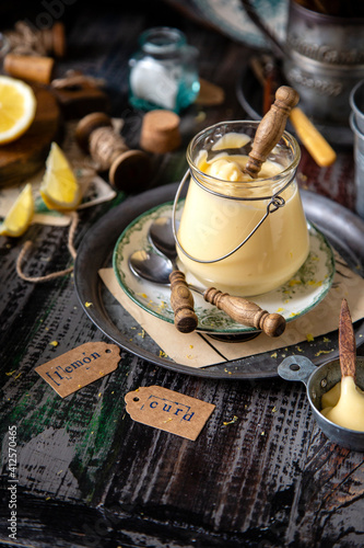 Fototapeta Naklejka Na Ścianę i Meble -  homemade tasty smooth lemon cream (curd) in glass jar on vintage plates on wooden table. selective focus