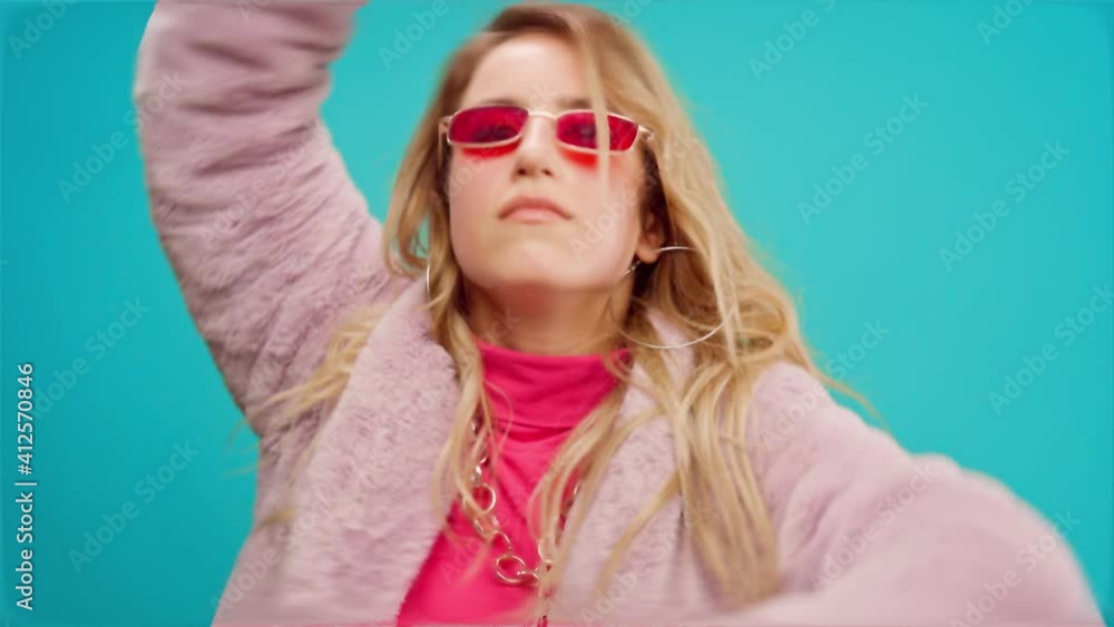 Stylish young woman in pink moving to the rythm against mint background Stylish young woman in pink moving to the rythm against mint background