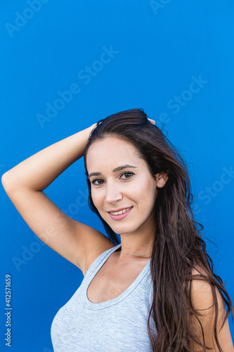 Portrait of a beautiful young woman smiling and posing with a blue wall in the background