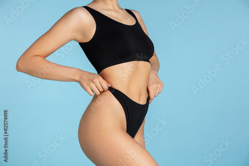 Belly. Beautiful body of young caucasian woman isolated on blue studio background. Fit, healthy and strong authentical body. Natural beauty, treatment, healthcare, fitness and diet concept.