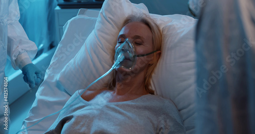 Foto Covid 19 infected patient with oxygen mask lying on bed in quarantine room