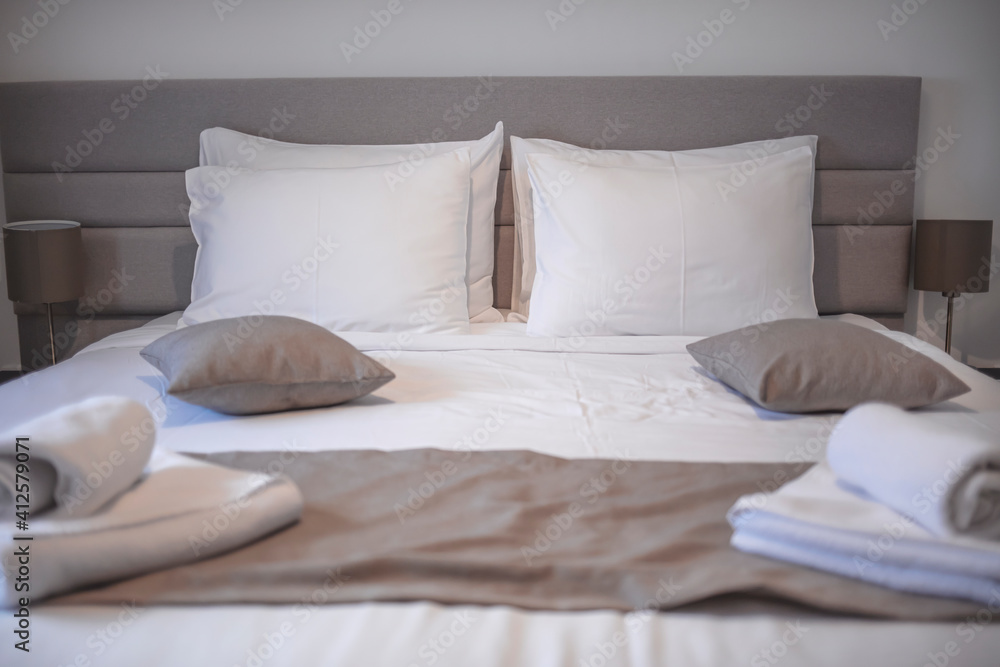 Modern bedroom with white bed. Bed maid-up with clean white pillows and bed sheets in beauty bedroom. Close-up. Interior background. Modern bedroom with bed and set of white color tone pillows Modern bedroom with white bed. Bed maid-up with clean white pillows and bed sheets in beauty bedroom. Close-up. Interior background. Modern bedroom with bed and set of white color tone pillows