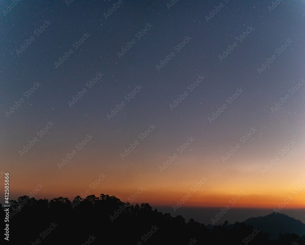 Predawn clear sky with orange horizon and blue atmosphere with Amazing Star Night and cloudy mountains