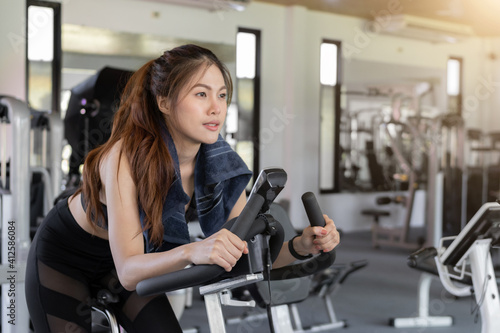 Fitness woman biking in gym, exercising cardio workout cycling bikes