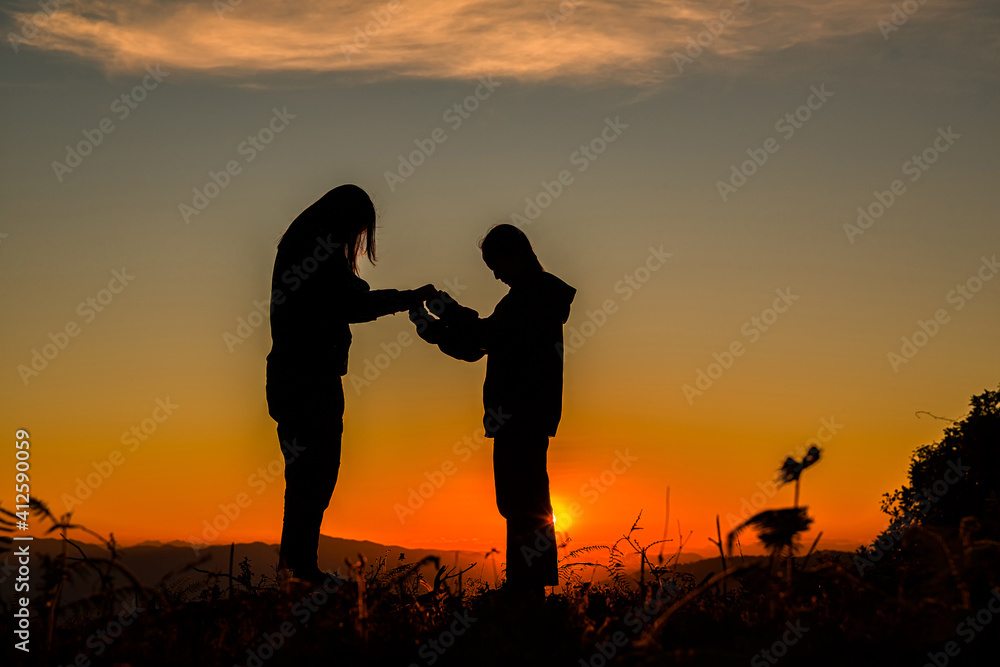 Two girl bowed and prayed at sunset in the mountains