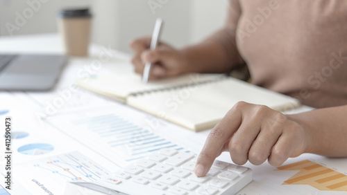 Head of accounting is recording the company's financial growth statistics using graphs as a reference for reviewing and analyzing the results, Taking notes and analyzing data graphs in office.