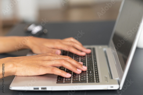 Close up image of female elegant hands typing text on the laptop keyboard, businesswoman responding to the client e-mail, buying ordering items online. Internet and modern wireless technology concept