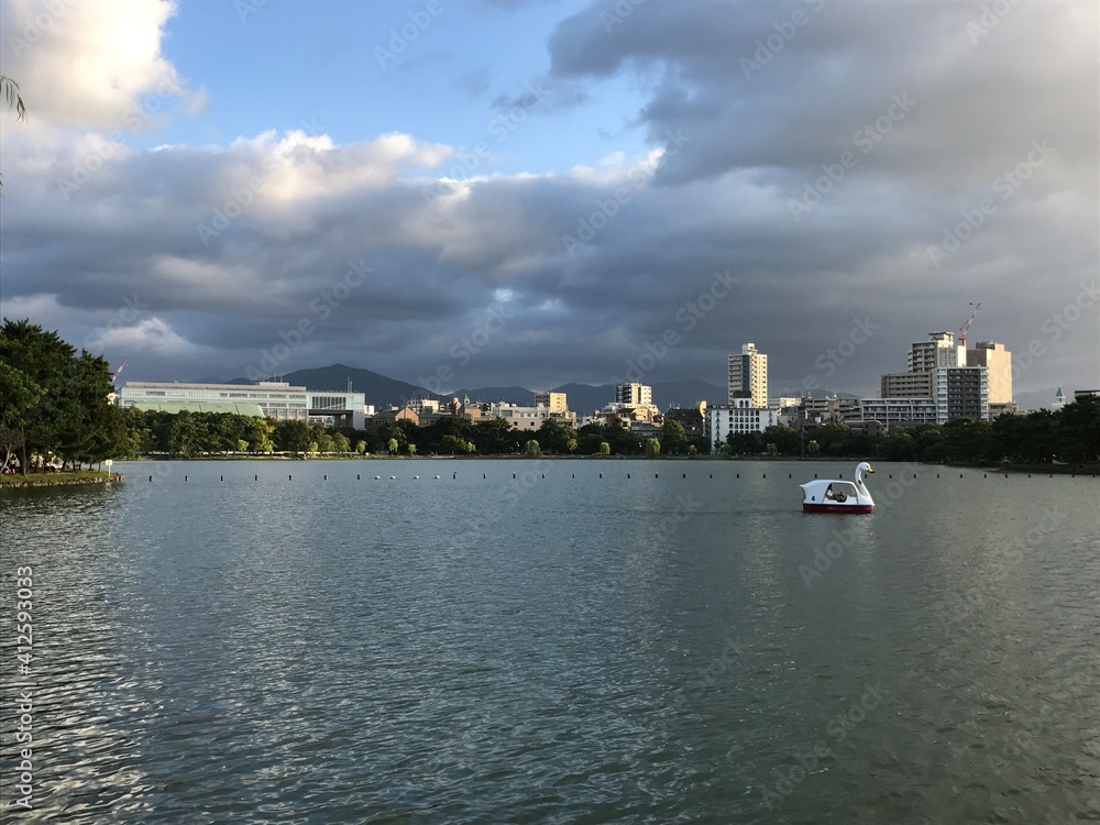 A lake with buildings and clouds in background