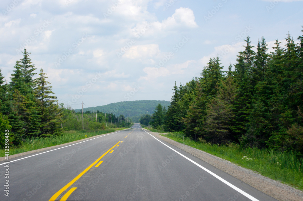 straight empty road with yellow line leading to green mountain straight empty road with yellow line leading to green mountain