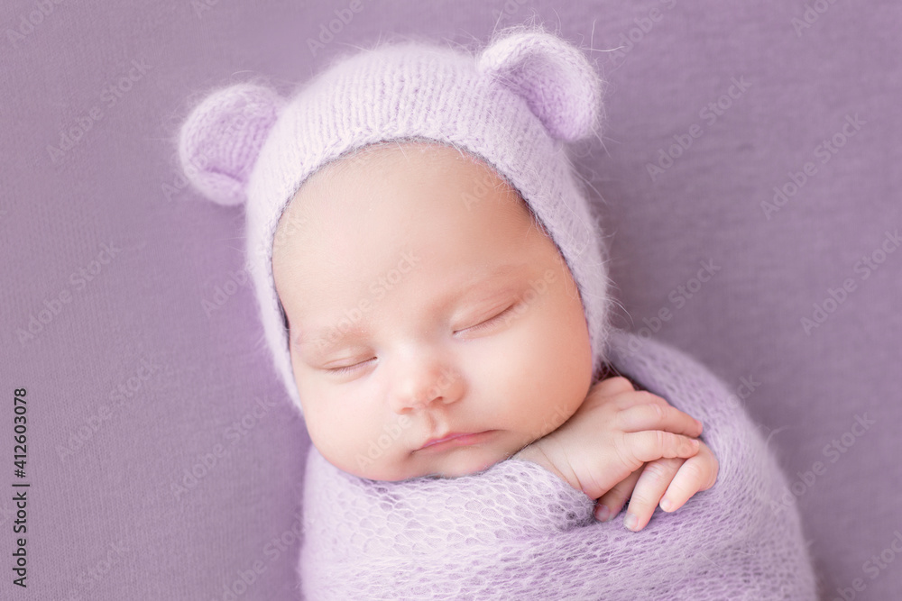 Newborn baby girl on a gray background in a hat with ears. A sweet newborn baby is sleeping. The first photo session of the baby. Newborn baby girl on a gray background in a hat with ears. A sweet newborn baby is sleeping. The first photo session of the baby.