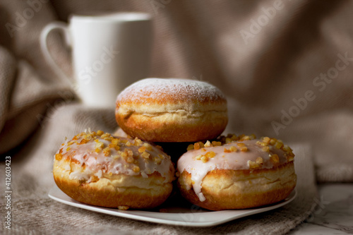 Close up on traditional polish donuts, served on Fat Thursday, selective focus, coffee cup at the background