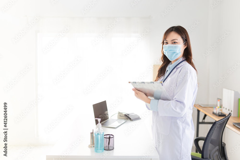 asian female doctor order medicine on patient chart in hospital, she wear surgical mask, treatment information asian female doctor order medicine on patient chart in hospital, she wear surgical mask, treatment information