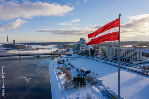 Panorama view of the Riga city with a big Latvian flag by the river Daugava. Latvian spirit.