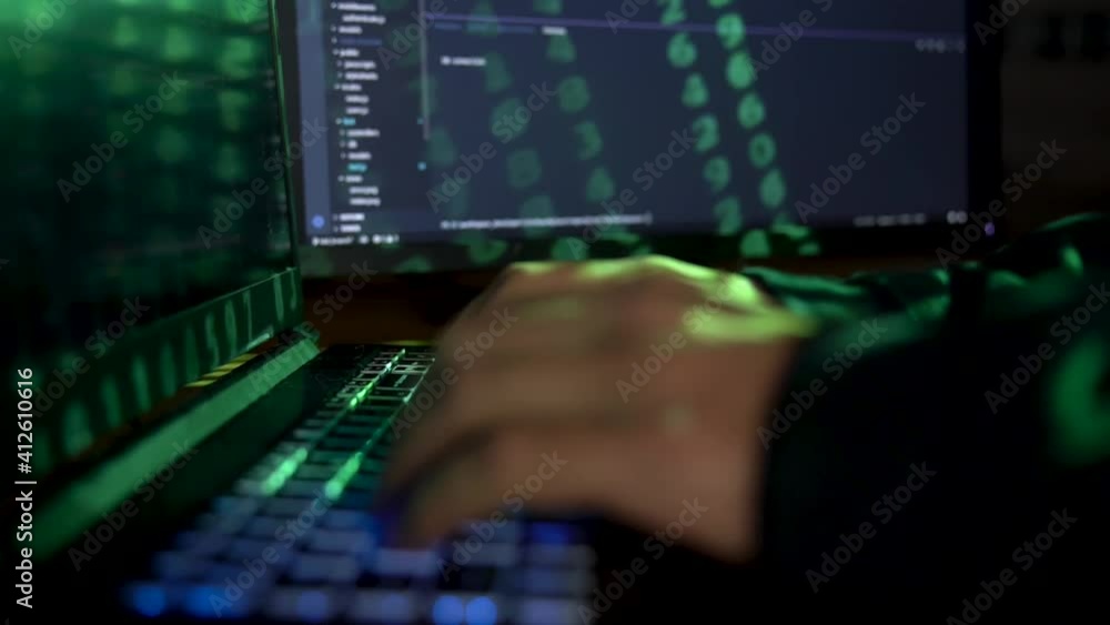 Closeup female hands is hacking password. Programmer software developer is typing malware virus on laptop keyboard to steal data. Binary code appears from projector light. Hacker attack concept. Closeup female hands is hacking password. Programmer software developer is typing malware virus on laptop keyboard to steal data. Binary code appears from projector light. Hacker attack concept.