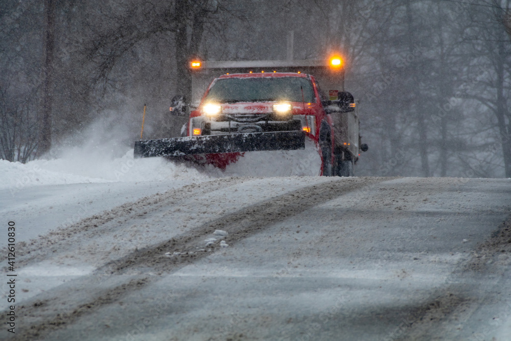 Snowplow in action clearing residential roads during snow storm Snowplow in action clearing residential roads during snow storm