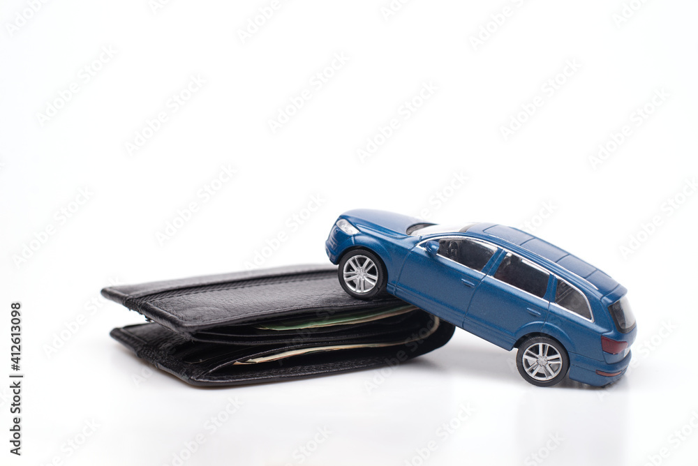 Close-up conceptual image of a blue toy car on a black wallet representing car loans, debts and related expenses. credit and insurance. On white background Close-up conceptual image of a blue toy car on a black wallet representing car loans, debts and related expenses. credit and insurance. On white background