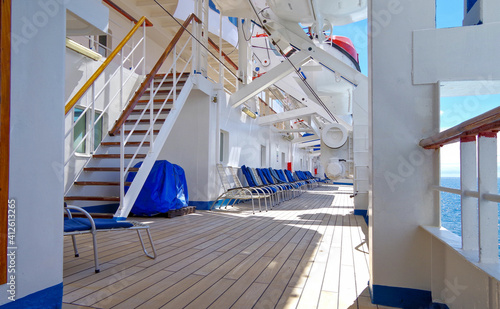 Sun loungers or deck chairs on outdoor boat or promenade deck of classic cruiseship or cruise ship liner with blue sky and superstructure during cruising photo